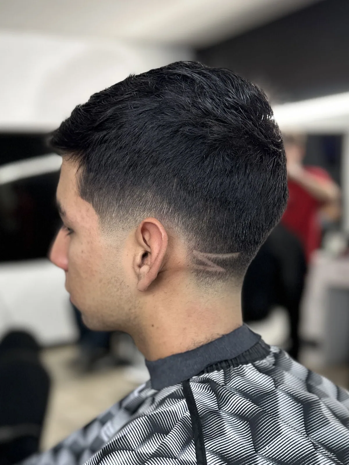 Low taper fade finished with a double-line design behind the ear