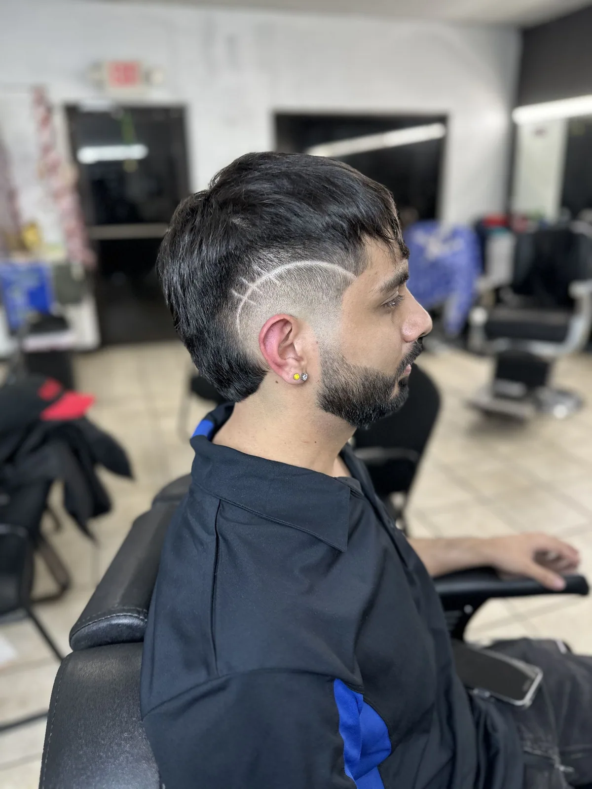 Burst fade with a sweeping freestyle line design and shaped beard